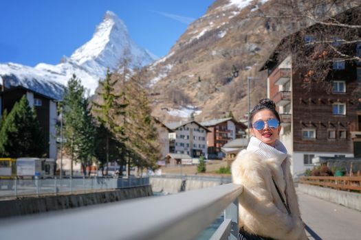 Young Woman Tourists see beautiful view of snow mountain Matterhorn in old town village in Zermatt, Switzerland.