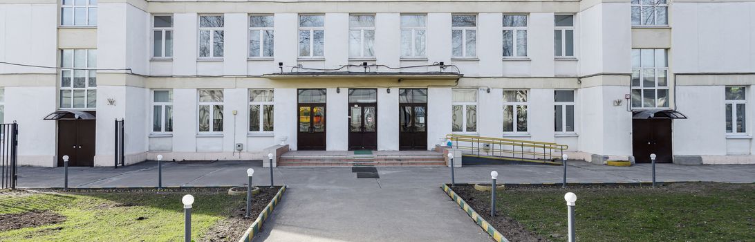 School building with an empty courtyard. Classic light plastered school house in Moscow, a typical building for educational institutions in the 30-50s