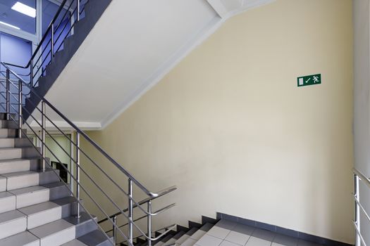The concept of the interior of an urban building. Photo of a staircase with metal railing between floors.