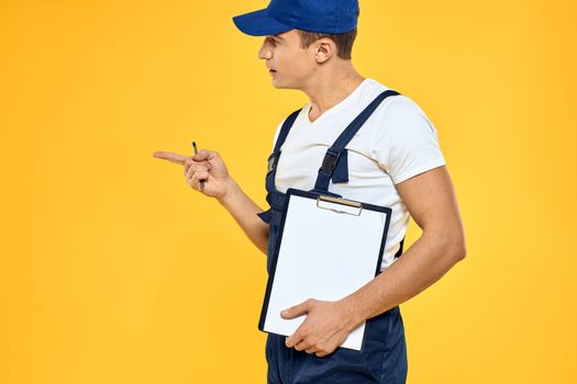 Man in working uniform documents rendering of services delivery service yellow background. High quality photo