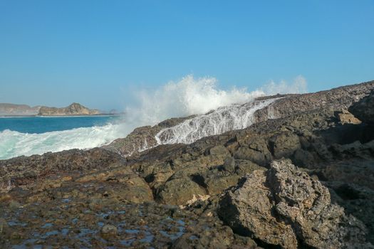 Ocean waves crashing on to lava rocks, Big Island of Lombok, Indonesia.