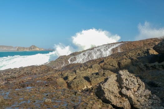 Ocean waves crashing on to lava rocks, Big Island of Lombok, Indonesia.