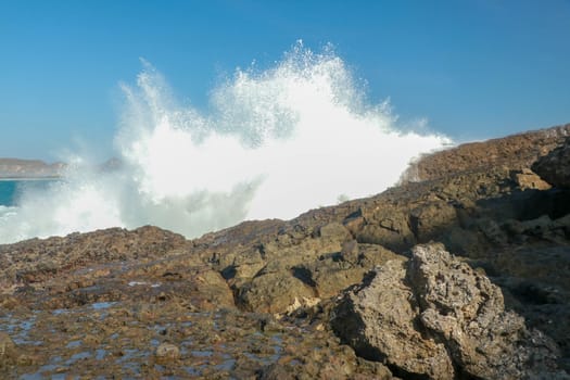 Ocean waves crashing on to lava rocks, Big Island of Lombok, Indonesia.