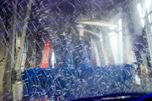 View from inside a car being washed at a car wash from the driver seat. Auto inside carwash from interior. Car windshield cleaning. Automatic conveyorized tunnel vehicle wash.