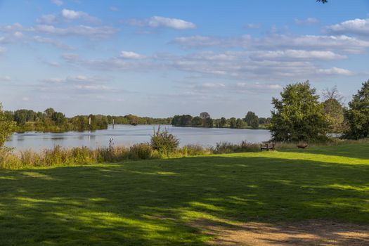 that landscape and nature of the river maas with lots of green,trees and place to sit with benches and fireplace for the evening