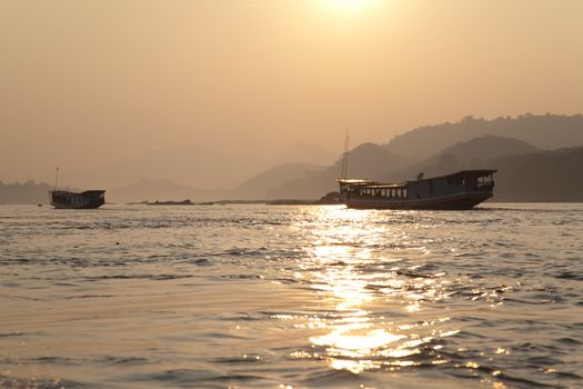 Nam Ou River, golden water at sunrise boats and landscape with mountains . High quality photo