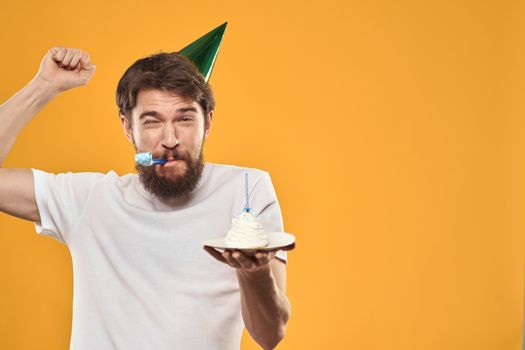 birthday boy in a cap with cake fun yellow background party. High quality photo