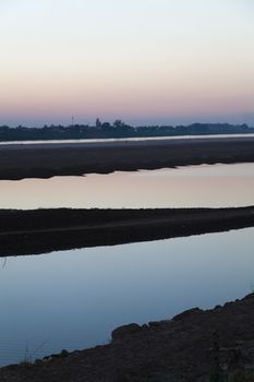 Mekong River, Vientiane, Laos at sunset, with silhouettes reflecting in water looking across the border to Thailand . High quality photo
