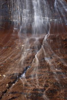 Beautiful waterfall streaming over red colored bedrock in the Left Fork North Creek, Zion National Park.