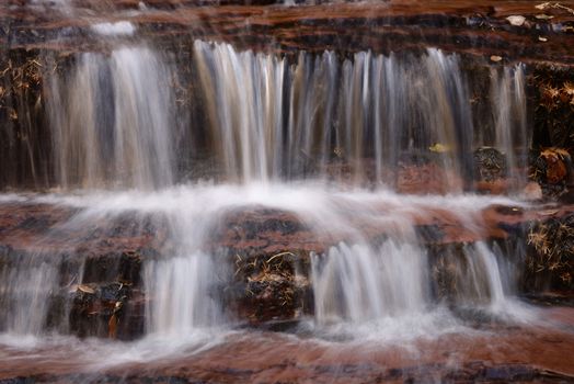 Beautiful waterfall streaming over red colored bedrock in the Left Fork North Creek, Zion National Park.