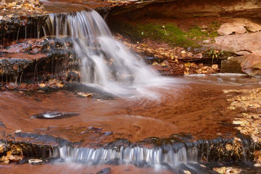 Beautiful waterfall streaming over red colored bedrock in the Left Fork North Creek, Zion National Park.