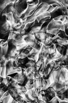 Abstract puffs of natural black smoke and white huge flame of strong fire design. Black and white photography, motion blur from fire, high temperature from flames. Dangerous firestorm abstract texture