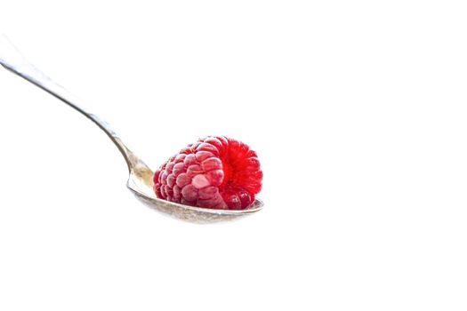 Ripe raspberry fruit lies in a silver spoon on a white background