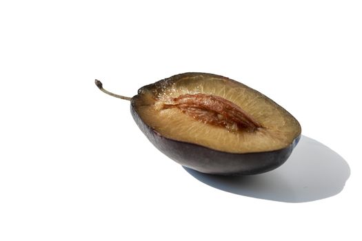 Half of plum fruit with a protruding piece of seed-stone, isolated against a white background