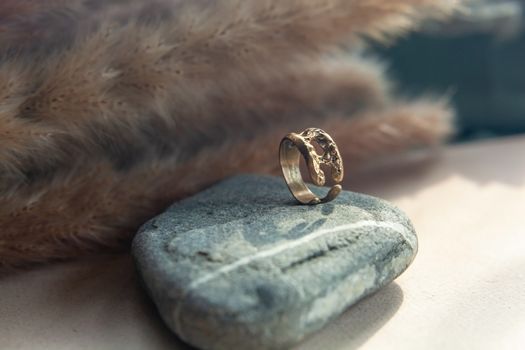 trendy vintage cast brass ring. jewelry womens ring abstract drawing closeup on a gray natural stone with shaddows