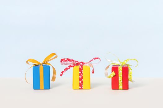 Three colorful gift boxes on a pastel background. Copy space. Front view.