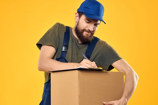 Worker male courier delivering boxes packaging documents yellow background. High quality photo