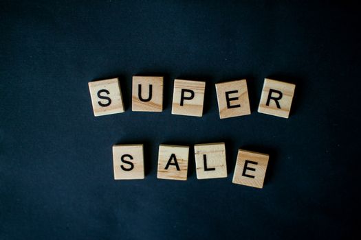 The inscription super sale from wooden blocks on a black background