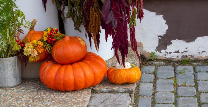 Orange pumpkins of various sizes lie on the porch of the house.The Concept Of Halloween.