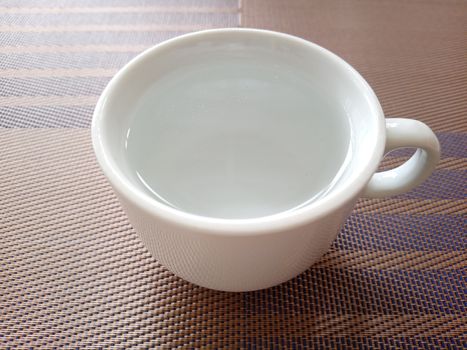 White coffee mug cup with hot water on top of brown table