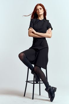 woman high chair indoors full length black dress red hair model boots. High quality photo