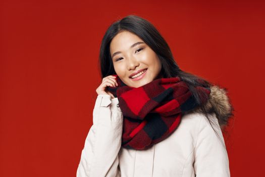 A beautiful woman with an Asian appearance is smiling at the camera on a red background