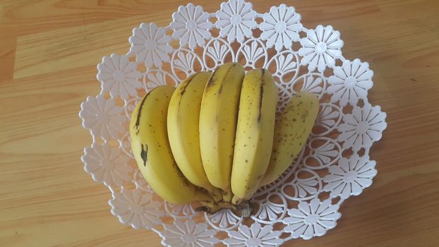 Close up view of cultivated ripe banana placed in plastic changair or container on a wooden floor. Fruit background for text