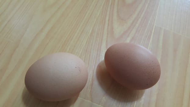 Fresh farm chicken eggs placed on a wooden floor under light in market for sale