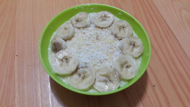Creamy tasty sweet custard with banana pieces layered on surface on wooden floor. A top view of home made custard, a dairy products for dessert after meal.