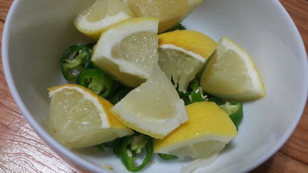 Top view of fresh lemon slices in a bowl over a wooden floor. Fruit background