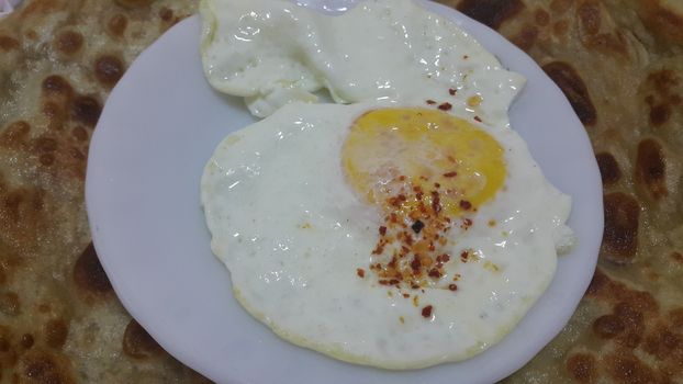 Top view of Fried egg or egg omelet on a white saucer or plate served with spines on it.