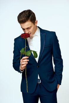 A man in a suit with a rose in his hands a gift date light background. High quality photo