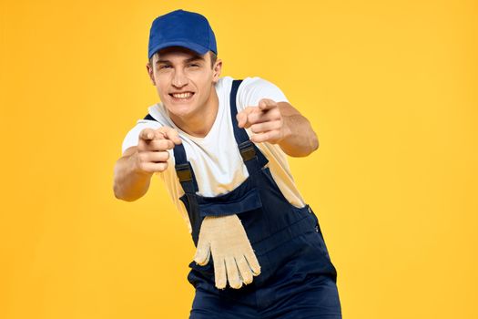 Working man in uniform of gloves rendering service yellow background. High quality photo