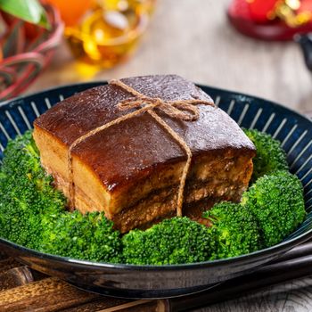 Dong Po Rou (Dongpo pork meat) in a plate with green vegetable, traditional festive food for Chinese lunar new year cuisine meal, close up.