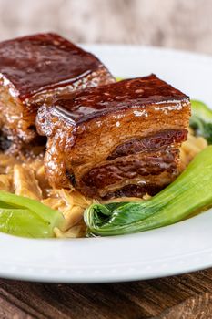 Dong Po Rou (Dongpo pork meat) in a plate with green vegetable, traditional festive food for Chinese lunar new year cuisine meal, close up.