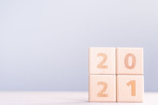 2021 New Year abstract design concept - Number wood block cubes isolated on wooden table and light mist blue background.