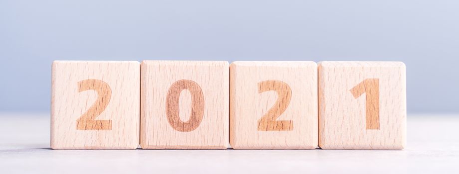 2021 New Year abstract design concept - Number wood block cubes isolated on wooden table and light mist blue background.