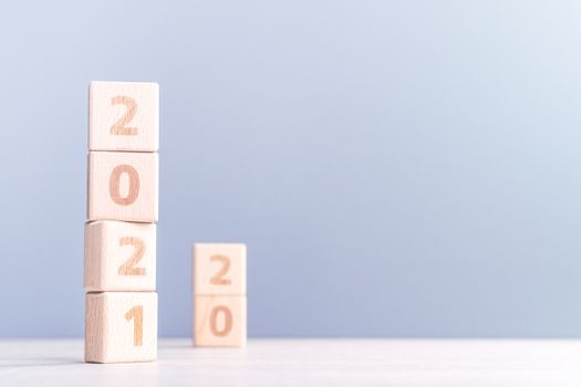 2021 New Year abstract design concept - Number wood block cubes isolated on wooden table and light mist blue background.