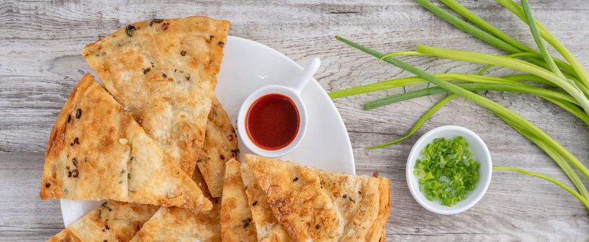 Taiwanese food - delicious flaky scallion pie pancakes on bright wooden table background, traditional snack in Taiwan, top view.