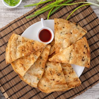 Taiwanese food - delicious flaky scallion pie pancakes on bright wooden table background, traditional snack in Taiwan, top view.