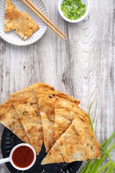 Taiwanese food - delicious flaky scallion pie pancakes on bright wooden table background, traditional snack in Taiwan, top view.