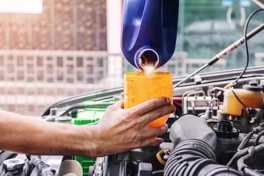 Auto mechanic is filling up the car's engine oil inside the auto repair center, the auto industry and garage ideas.