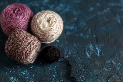 Four beige pink brown Color balls skein of wool yarn for crochet and knit on dark blue texture putty concrete. Flatlay image with space for text.