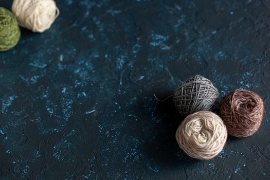 Color balls skein of wool yarn for crochet and knit on dark blue texture putty concrete. Flatlay image with space for text.