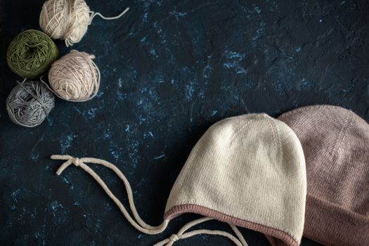 Color balls skein of wool yarn for crochet and knit and hats on dark blue texture putty concrete. Flatlay image with space for text.