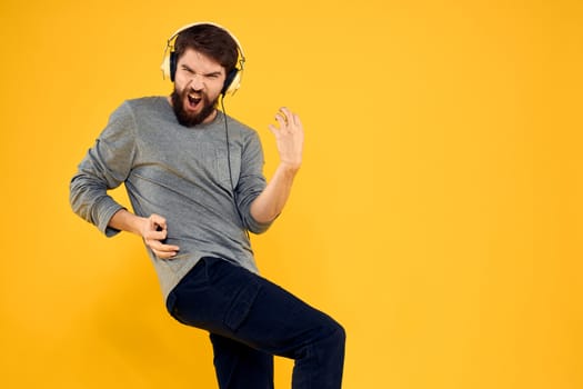 Man in headphones listens to music technology lifestyle fun people yellow background. High quality photo