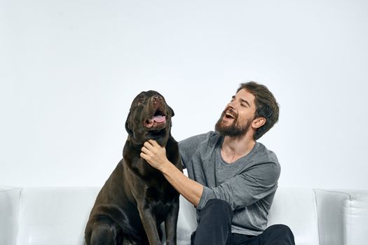 Man with a pet dog on the couch fun friends emotions light room. High quality photo
