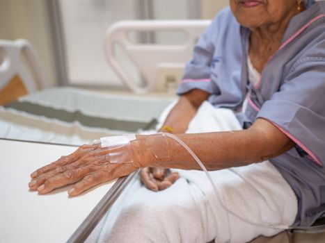 Saline solution drip on old women hand in hospital. Health care and Medical equipment concept.