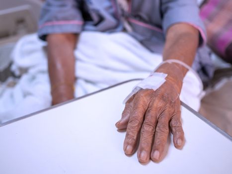 Saline solution drip on old women hand in hospital. Health care and Medical equipment concept.