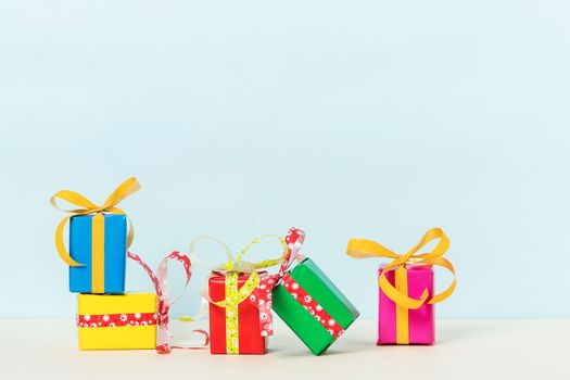 Five colorful gift boxes on a pastel background. Copy space. Front view.